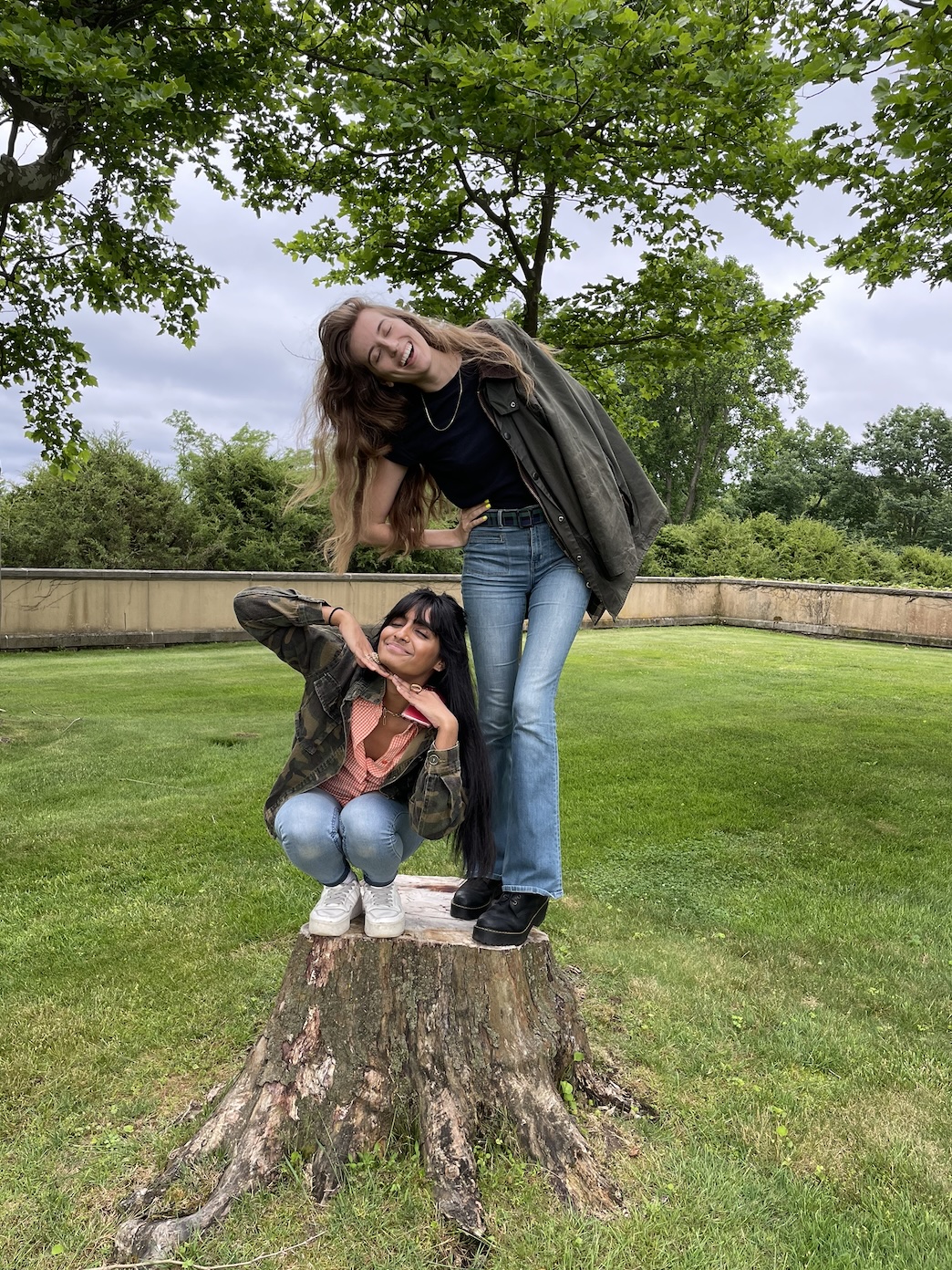 Andrea and Rtusha standing on a tree stump, laughing